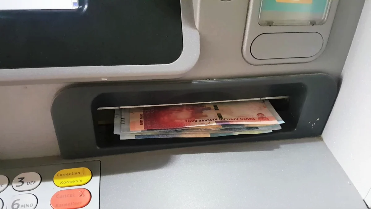 Person withdrawing South African rand notes from an ATM after a grant payment